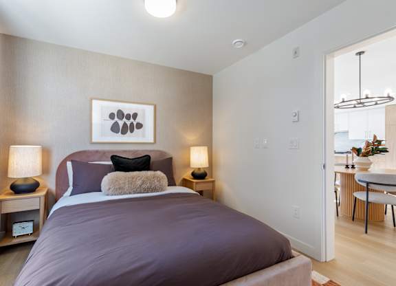 A bedroom with a large bed and a painting above it in Hillcrest Ave located in Abbotsford, BC