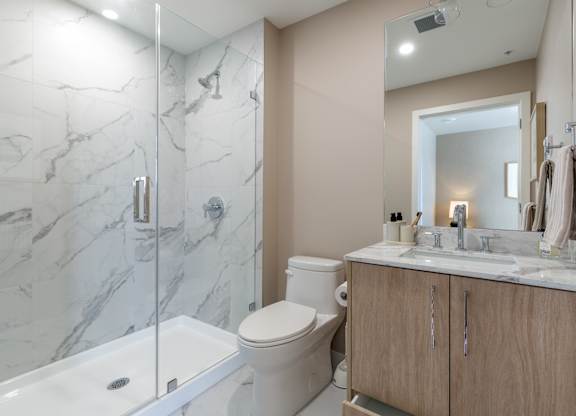 A bathroom with a marble tile shower and a white toilet in Hillcrest Ave located in Abbotsford, BC
