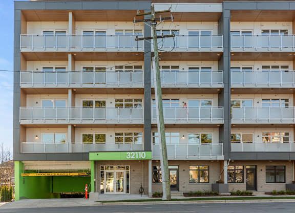 Image of  modern apartment building Hillcrest Ave with balconies and a green awning located in Abbotsford, BC