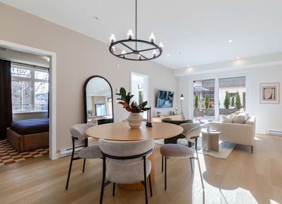 A modern dining room with a round table and grey chairs in Hillcrest Ave located in Abbotsford, BC