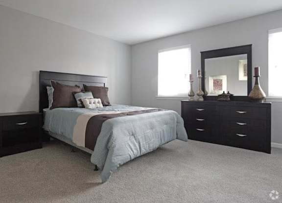 A bedroom with a bed, dresser, and mirror.