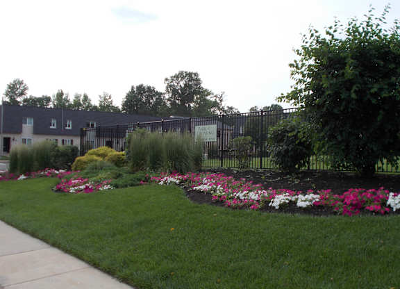 A garden with a fence and flowers in the foreground.