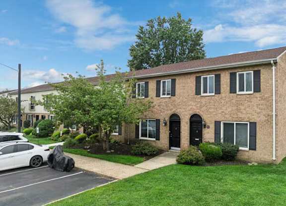 A white car is parked in front of a brick house.