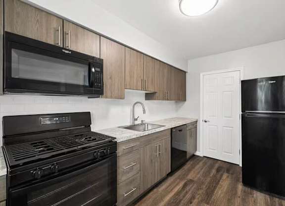 A black stove and microwave in a kitchen with wooden cabinets.