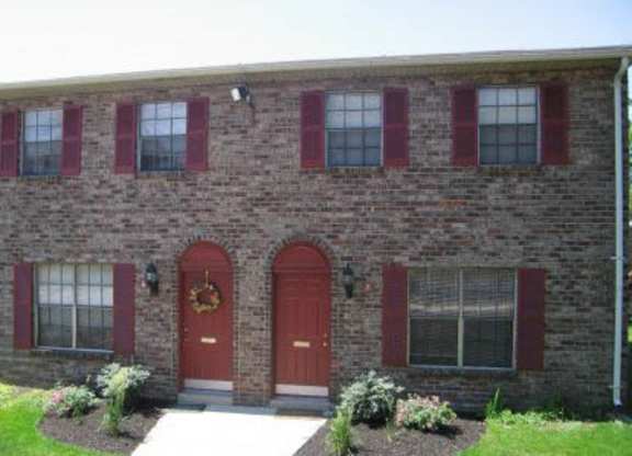 A brick house with a red door and red shutters.