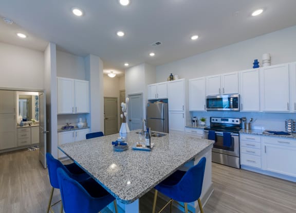 Modern kitchen with granite island and blue bar stools at Ciel Luxury Apartments, Jacksonville, FL