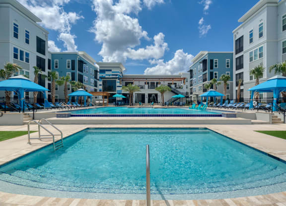 Resort style pool deck with blue umbrellas and spa at Ciel Luxury Apartments, Jacksonville