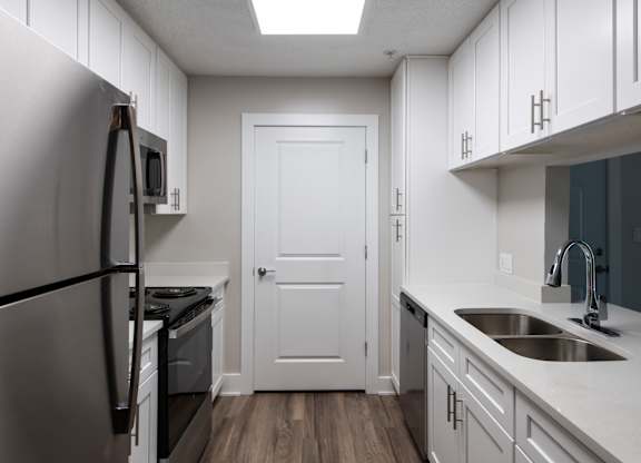 A kitchen with a white door and a stainless steel refrigerator.