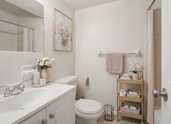A bathroom with a toilet, sink, and a towel rack.