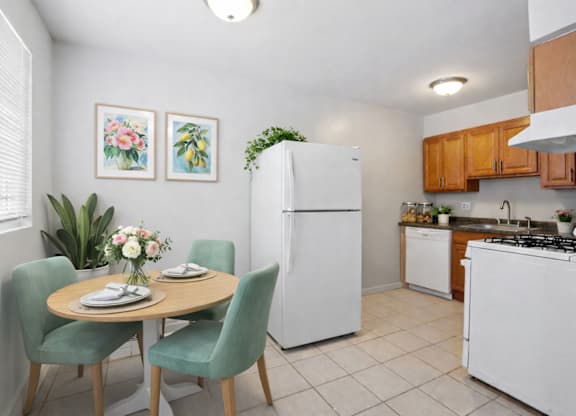 A kitchen with a table and chairs and a fridge.