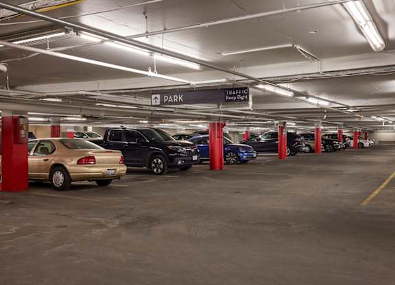 A parking garage with cars parked in red pillars.