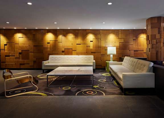A modern living room with a white sofa and a wooden backdrop.