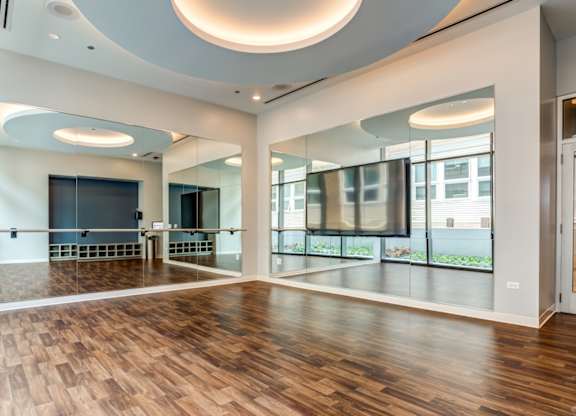A spacious room with wooden floors and a curved ceiling light.