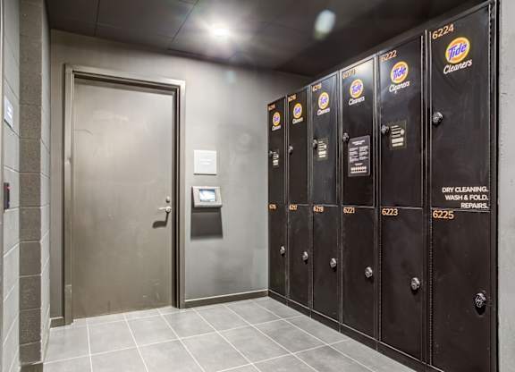 A row of Tide laundry detergent vending machines are lined up in a hallway.