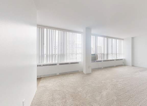 A white room with a carpet floor and a radiator.