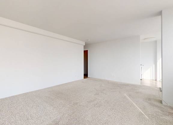 A large, empty room with a carpeted floor and white walls.