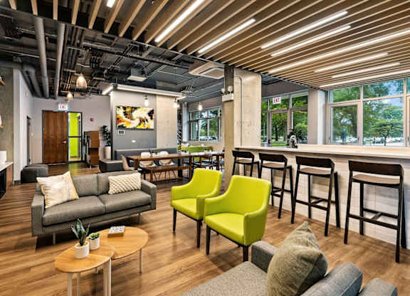A modern living room with a grey couch, a green chair, and a wooden coffee table.