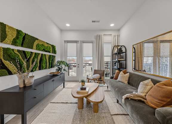 A living room with a grey couch and a large painting on the wall.at Adler Montford Park + Drexel Townes, Charlotte, NC, 28209