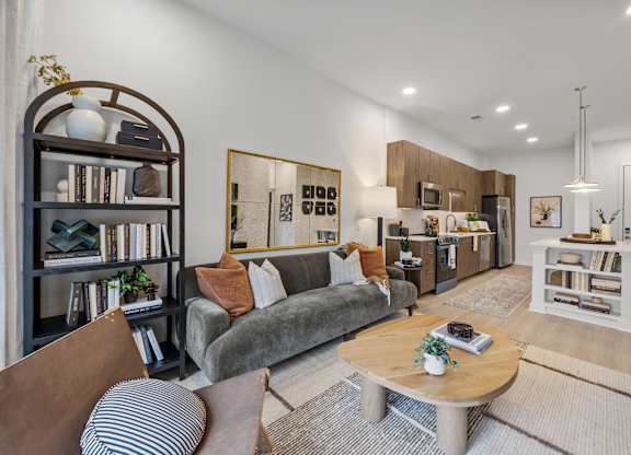 A living room with a grey couch, a coffee table, and a bookshelf.at Adler Montford Park + Drexel Townes, Charlotte, NC, 28209