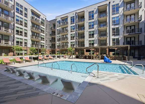 A large swimming pool in front of apartment buildings.