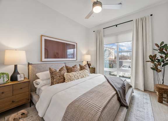 A bedroom with a large bed, a ceiling fan, and a window with curtains.at Adler Montford Park + Drexel Townes, Charlotte, NC, 28209
