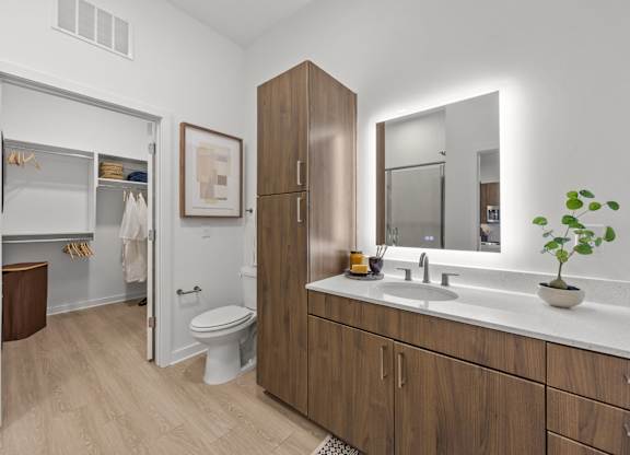 A bathroom with a toilet, sink, and mirror.at Adler Montford Park + Drexel Townes, Charlotte, NC, 28209