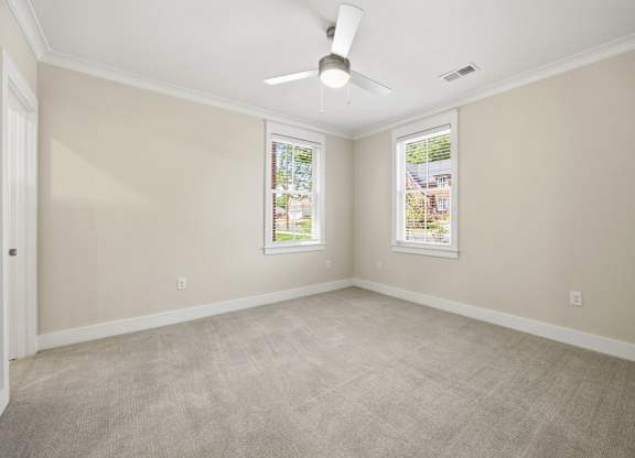 A room with a ceiling fan and two windows.