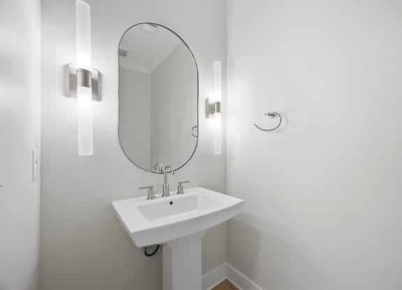 A white sink with a round mirror above it.