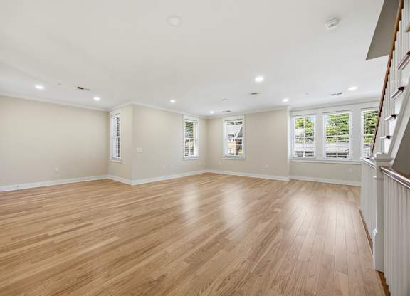 A spacious room with wooden flooring and white walls.