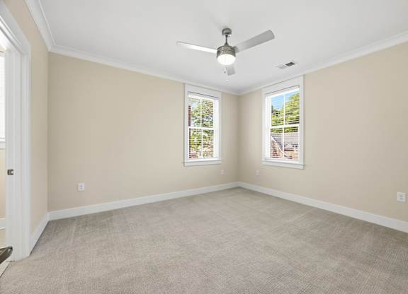 A room with a ceiling fan and two windows.