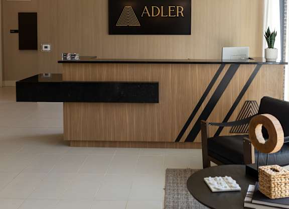 A reception area with a black and gold reception desk and a sign that says "ADLER".