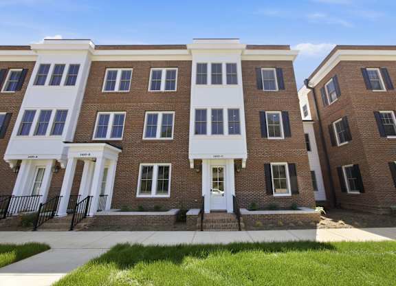 A row of brown and white townhouses with black railings.