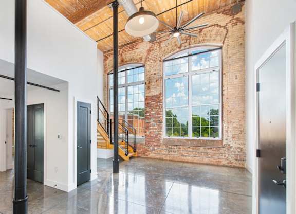 A large open space with a brick wall and a staircase. at Judson Mill Lofts and The Jenny & Westervelt in Greenville, SC