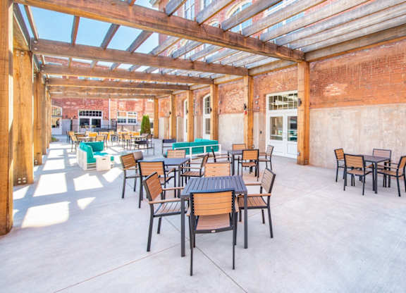A patio with tables and chairs is covered by a roof. at Judson Mill Lofts and The Jenny & Westervelt in Greenville, SC