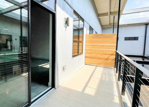 A glass door is open to a hallway with a wooden wall at Judson Mill Lofts and The Jenny & Westervelt in Greenville, SC