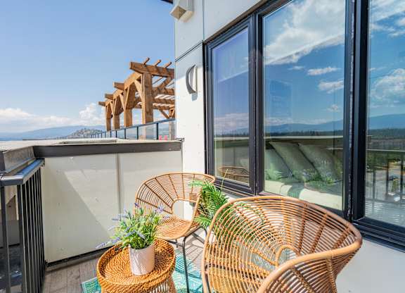A balcony with a table, two chairs, and a potted plant.