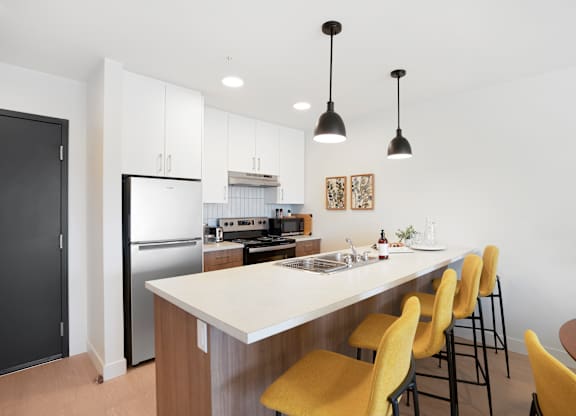 A kitchen with a white island and yellow chairs.