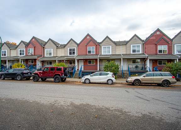 A row of houses with cars parked in front.