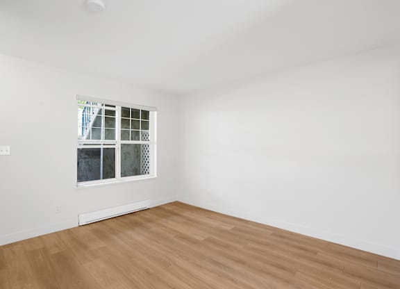 A room with a window and wooden flooring.