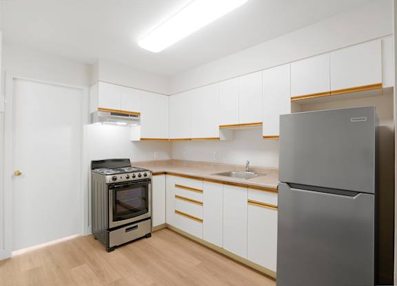 A kitchen with a stove, sink, and refrigerator.