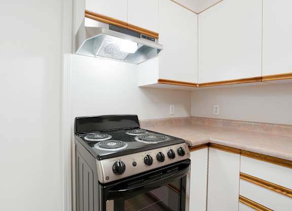 A black and silver stove in a kitchen with white cabinets.