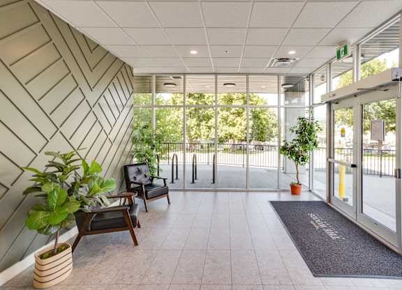 A hallway with a bench, potted plants, and a door.
