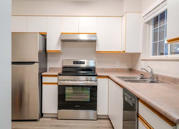 A kitchen with a stainless steel refrigerator, oven, and dishwasher.