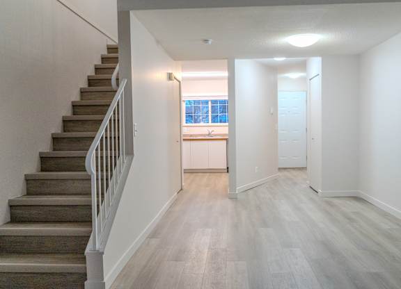 A long hallway with a staircase on the left and a door on the right.