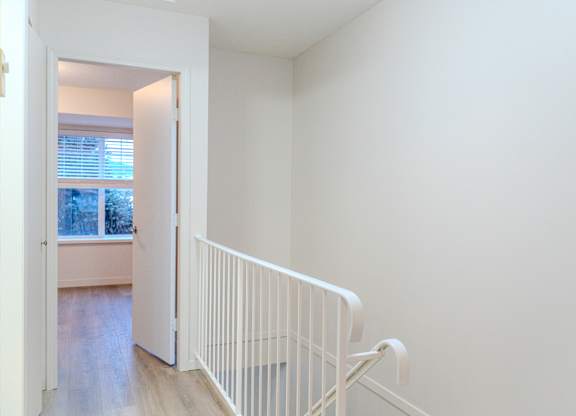 A white railing in a room with a view of a window.
