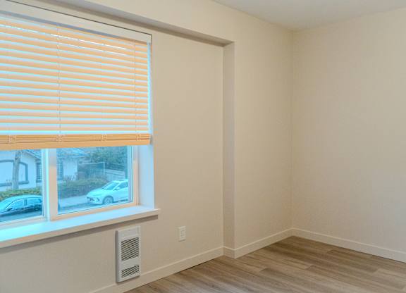 A room with a window and a vent on the wall.