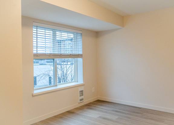 A room with a window and a wooden floor.