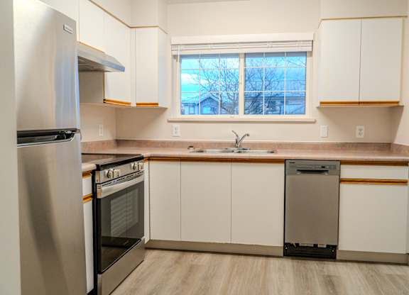 A kitchen with white cabinets and a stainless steel refrigerator.