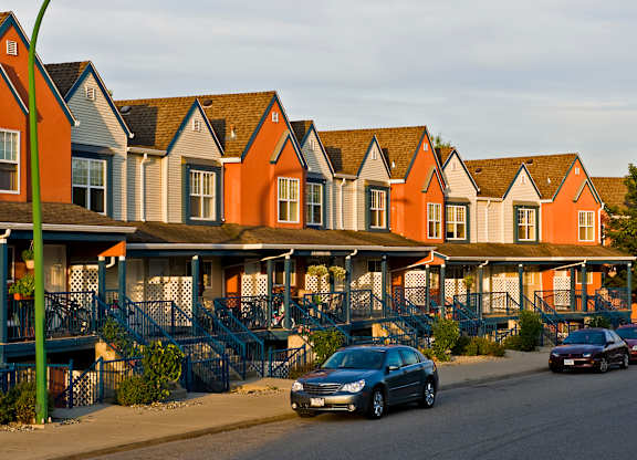 A row of houses with cars parked in front.