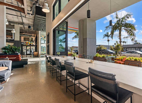 Indoor outdoor workspace with bar seating and palm trees at AMP 30 Apartments, San Diego, CA 92116